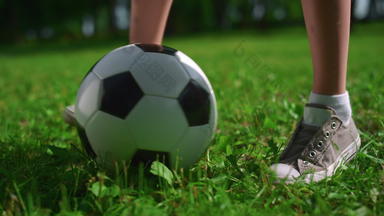 未知的孩子们脚玩足球草关闭男孩腿踢球公园